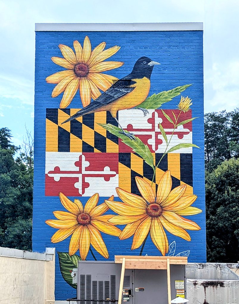 Public art murals by Yulia Avgustinovich on the tower of Landover Hills Town Hall in Maryland, featuring Maryland state symbols, the American flag with a bald eagle, and the Town of Landover Hills seal.