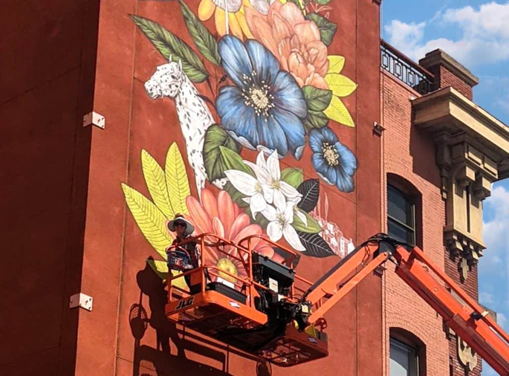 Artist Yulia Avgustinovich painting a large-scale mural using an 86-foot lift in downtown Boise, Idaho.