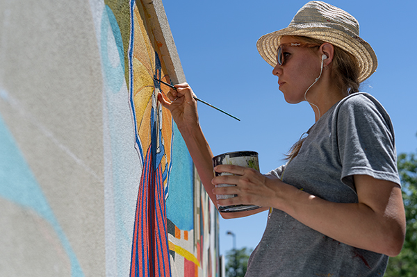 yulia-avgustinovich-painting-fox-theater-mural-aurora-co public art mural artist Yulia Avgustinovich painting a four-wall mural at the Fox Theater in Aurora, Colorado, depicting the theater’s historic legacy.