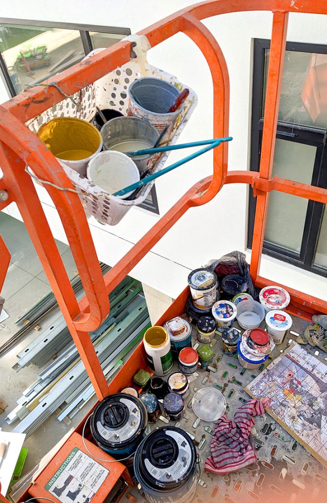 Artist painting large-scale mural using boom lift in Caldwell Idaho.