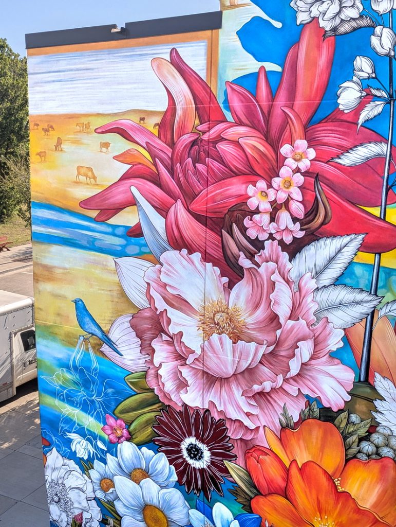 Public art mural at Space to Create in Ridgway, CO with flowers, birds and grassy field.