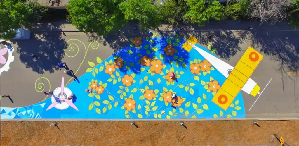 Community volunteers painting a large-scale street mural in Aurora, Colorado during a public art project.