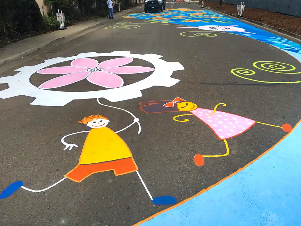 Close-up detail of painted asphalt mural showing graphic elements and street-marking paint texture.