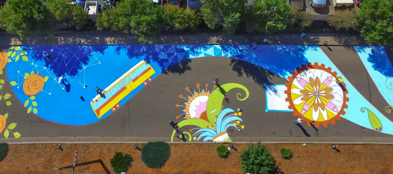 Community volunteers painting a large-scale street mural in Aurora, Colorado during a public art project.