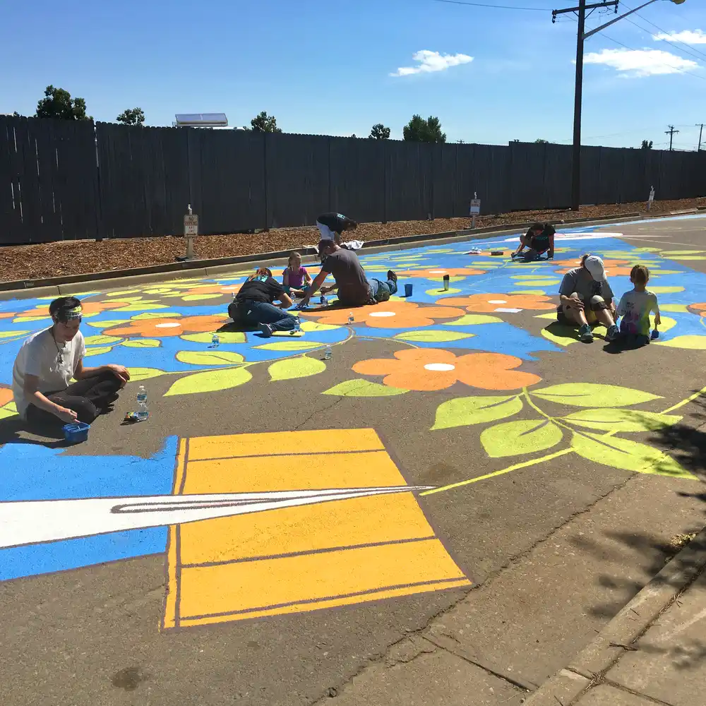 Community volunteers painting a large-scale street mural in Aurora, Colorado during a public art project.