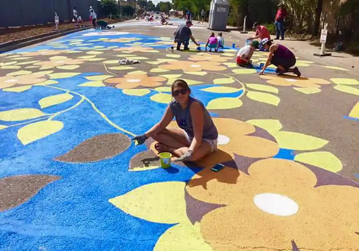 Community volunteers painting a large-scale street mural in Aurora, Colorado during a public art project.