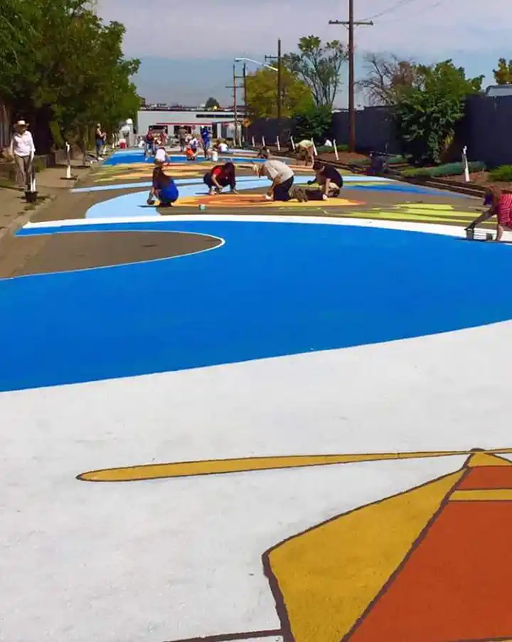 Community volunteers painting a large-scale street mural in Aurora, Colorado during a public art project.