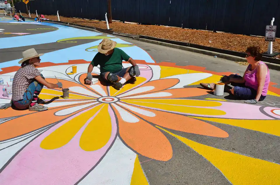 Community volunteers painting a large-scale street mural in Aurora, Colorado during a public art project.